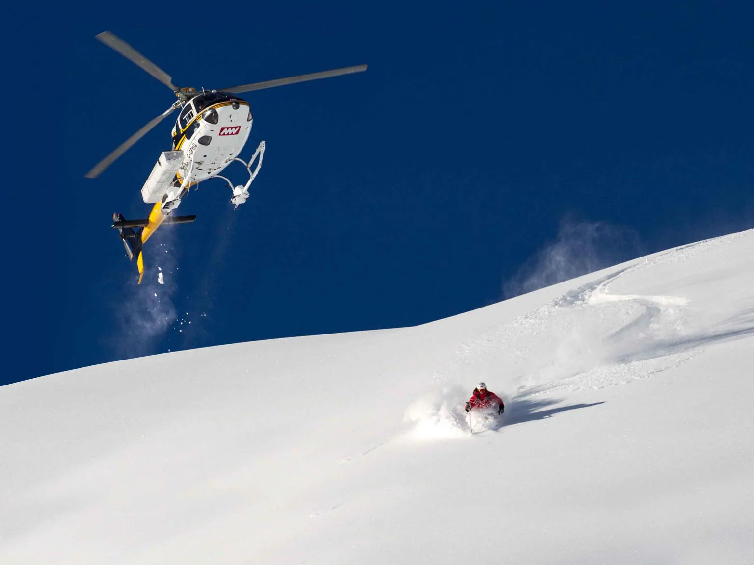 Helicopter and skier in alpine terrain