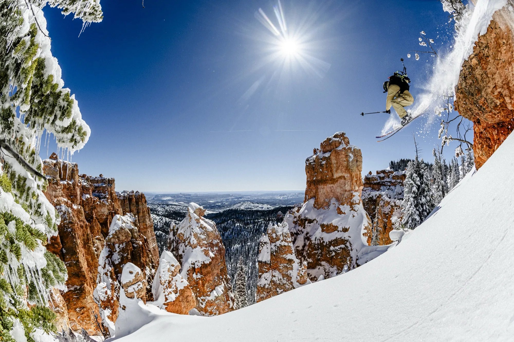 Skier airborne above snow-covered hoodoos in southern Utah