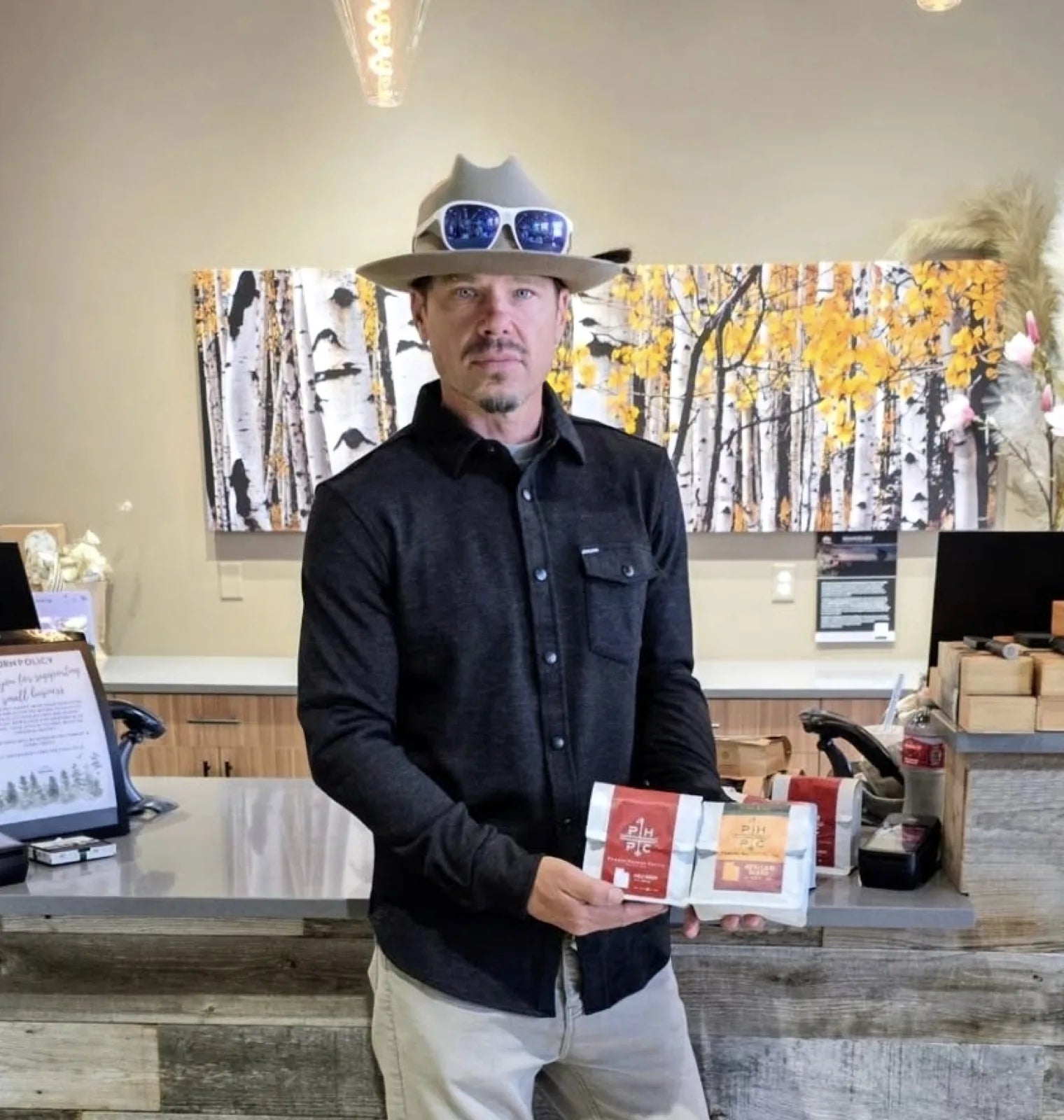 Mark, founder and roaster, holding bags of Powder Hounds coffee in the Park City shop
